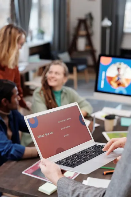 Persona muestra una presentación en una laptop durante una reunión de trabajo.
